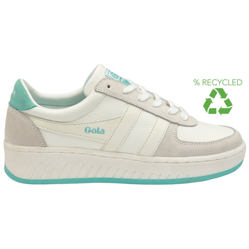 A women's grand slam chunky trainer by Gola. Its base is white, however it features off-white wingflashes and grey fabric detailing around the eyelaces and back of the shoe. The back upper, logo on the tongue and wingflash, and bottom sole is a contrasting light teal green. This shoe is recycled.